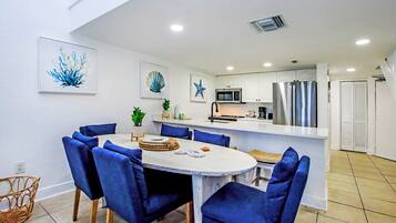 A modern kitchen with white cabinets, a stainless steel refrigerator, and a microwave.