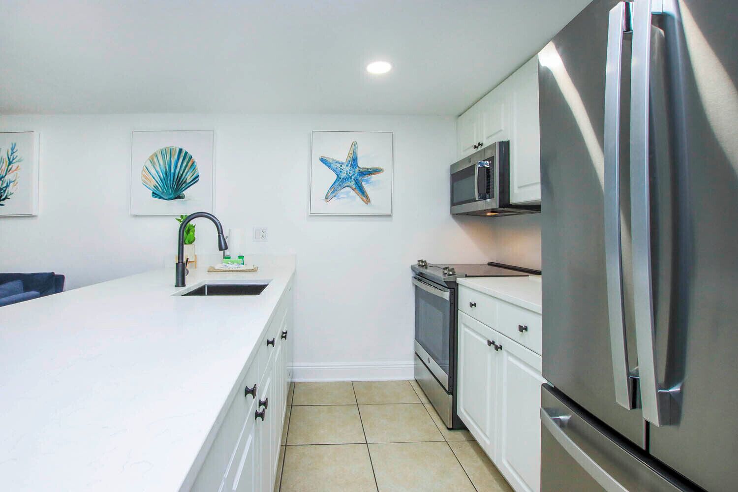 Una cocina moderna con armarios blancos, electrodomésticos de acero inoxidable y decoración en la pared.