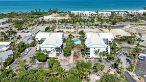 Luchtbeeld van een resort met twee opvallende gebouwen, een parkeerplaats en een strand op de achtergrond.