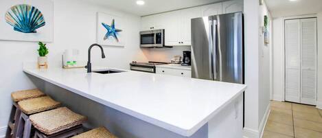 Una cocina moderna con una isla grande, electrodomésticos de acero inoxidable y una pieza decorativa de arte mural con forma de estrella de mar.
