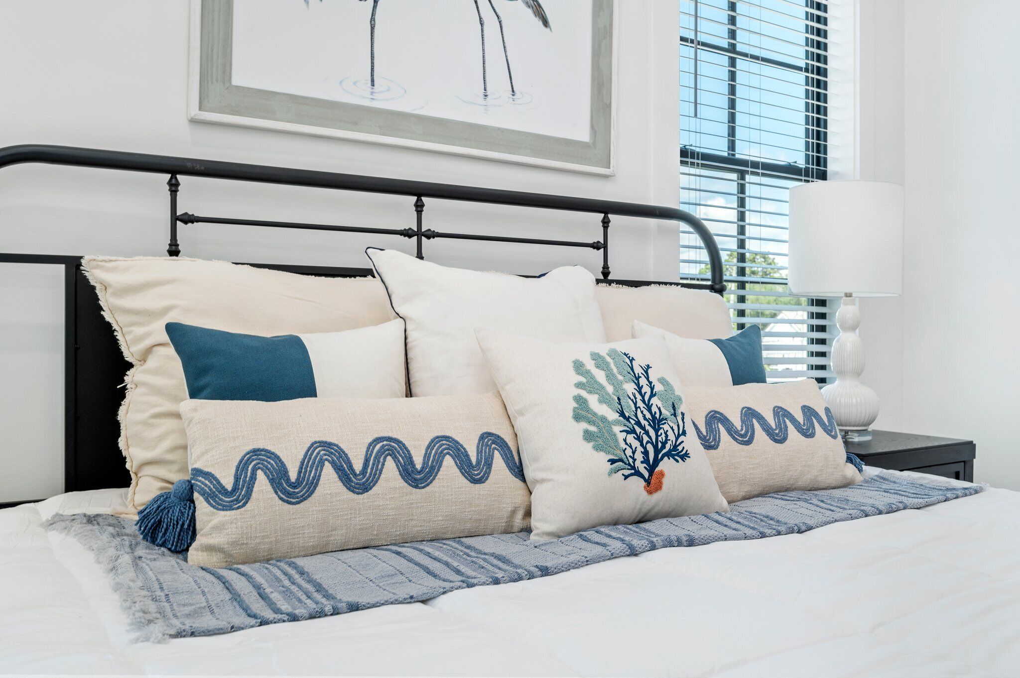 Cama bem arrumada com diversos travesseiros e um cobertor decorativo.