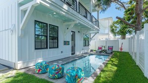 Uma casa moderna de dois andares com piscina, varanda coberta e gramado bem cuidado.