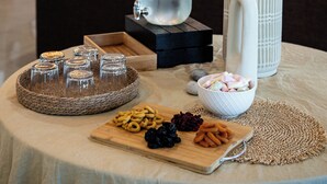 Una mesa redonda con aperitivos, una botella de agua y objetos decorativos en un ambiente interior moderno.