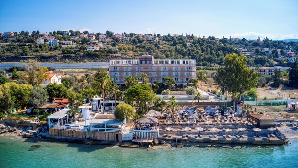 Un hotel frente al mar con un edificio grande, zona de estar al aire libre y vistas al océano.