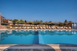 Una piscina al aire libre, sombrillas, sillones reclinables de piscina