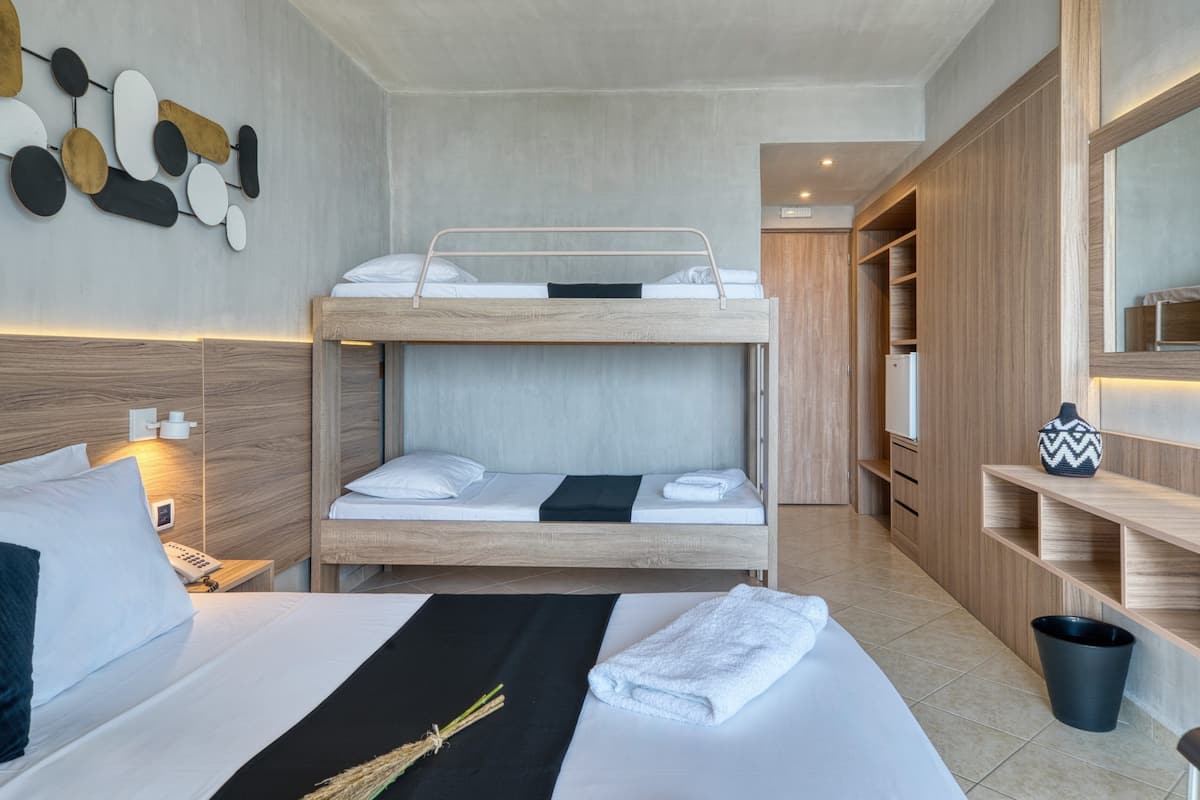 Ein Hotelzimmer mit Etagenbett, Nachttisch mit Lampe, Holzschrank und einer kleinen Ablagefläche mit Dekoration.