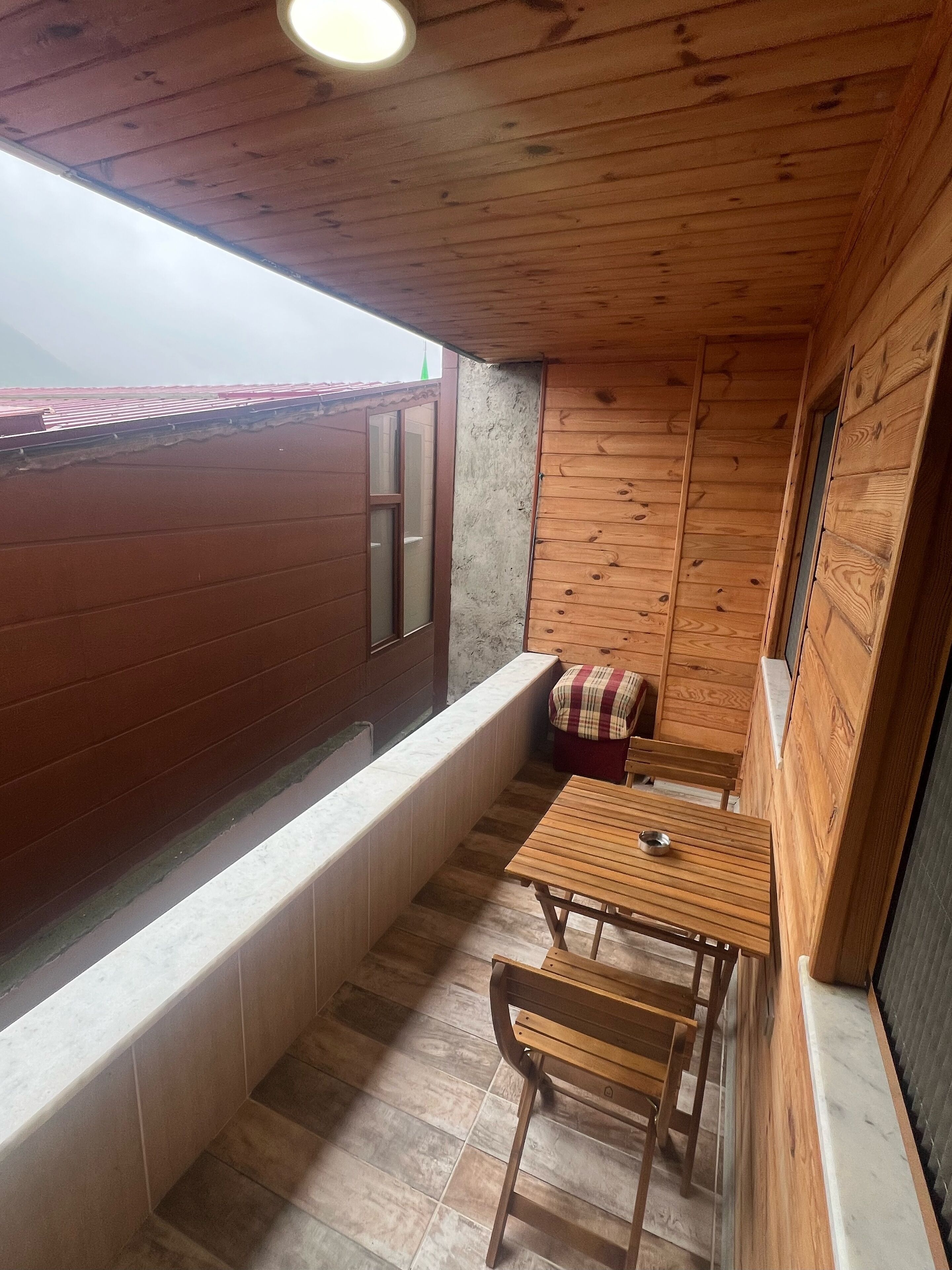 Un intérieur en bois avec un banc et une table, une fenêtre et une vue sur le toit.
