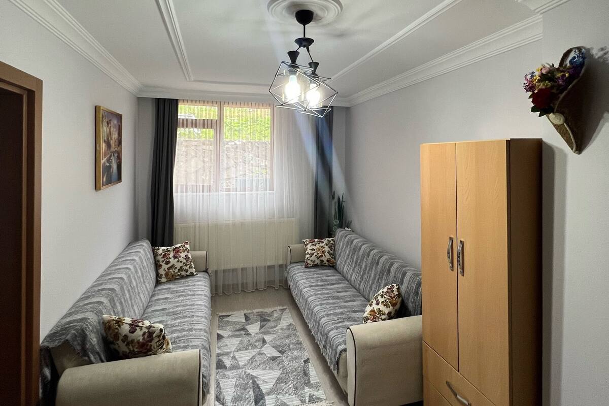 A room with two sofas, a wooden wardrobe, and a ceiling fan.