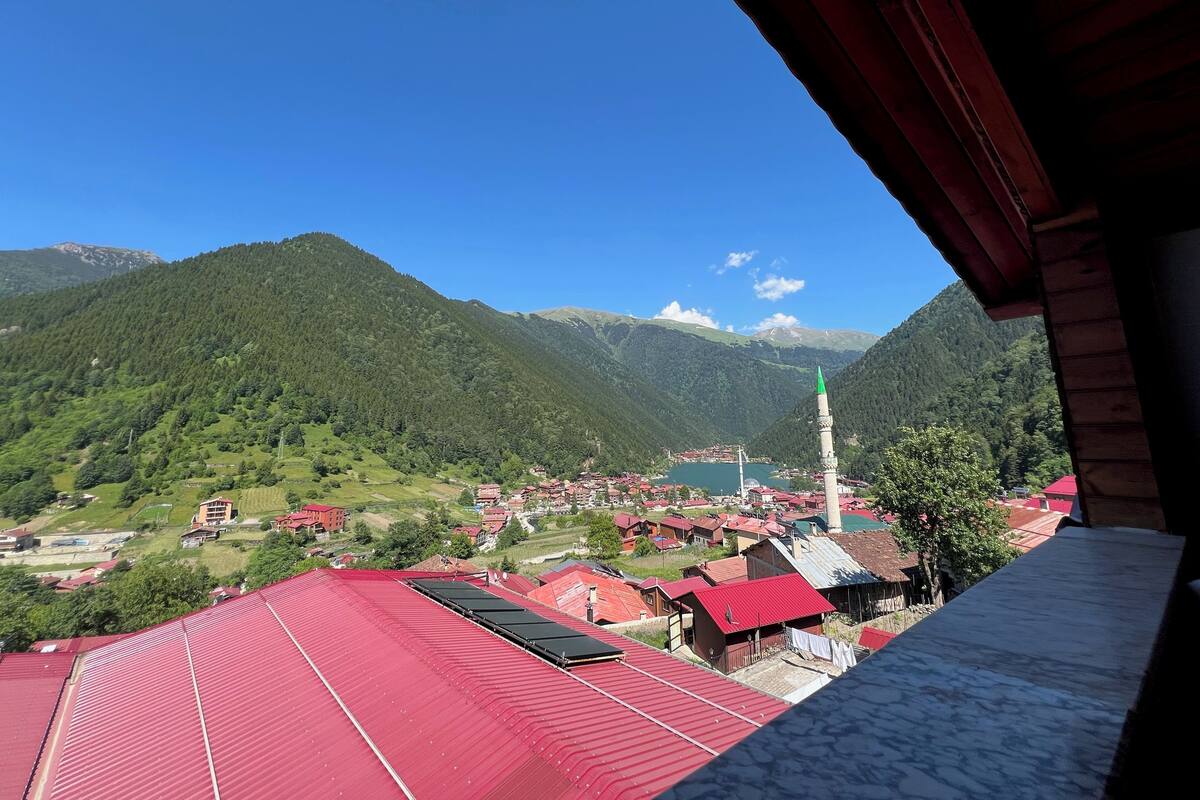 A mountainous landscape with a village, a prominent church tower, and a lake.