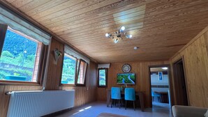 A wooden-paneled room with a large window, a ceiling fan, a clock, and a television. - DİLEK APART (Çaykara)