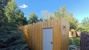 Un cobertizo de madera con puerta blanca, rodeado de follaje y un sendero de piedra.