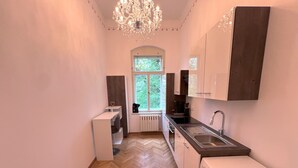 A compact kitchen with a herringbone floor, a built-in washing machine, and a window providing natural light. - 90qm Luxus Apartment im Schloss Cotta (Dohma)