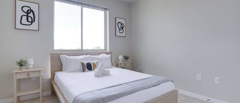 Une chambre moderne avec un grand lit, des tables de chevet et des œuvres d’art accrochées aux murs.