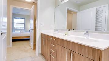 A modern bathroom with a large mirror, wooden cabinets, and a white countertop.