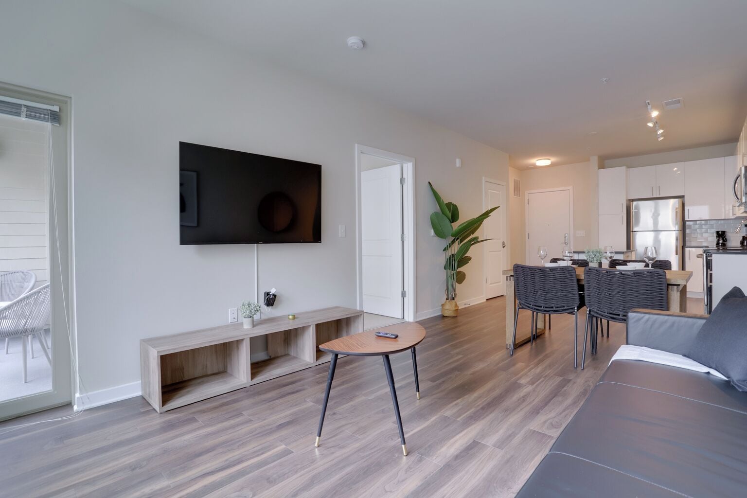 A modern living room with a flat-screen TV, a wooden bench, a round table, and a sofa.