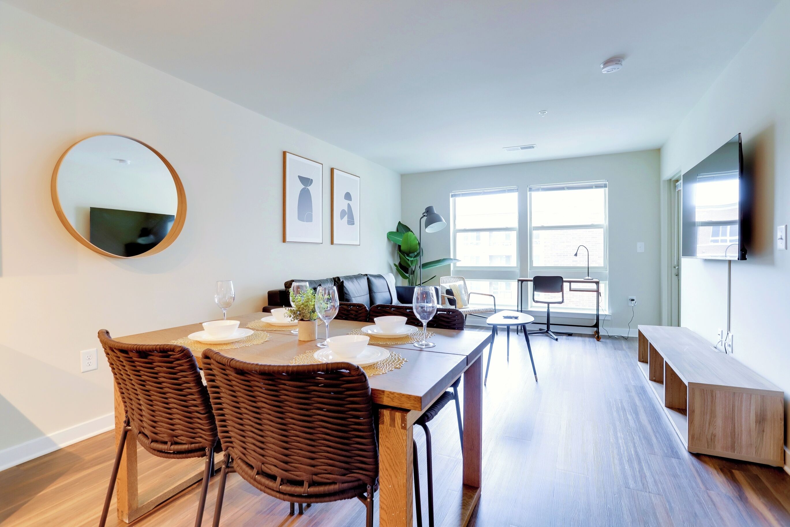 A modern living room with a dining area, a large mirror, and a flat-screen TV.