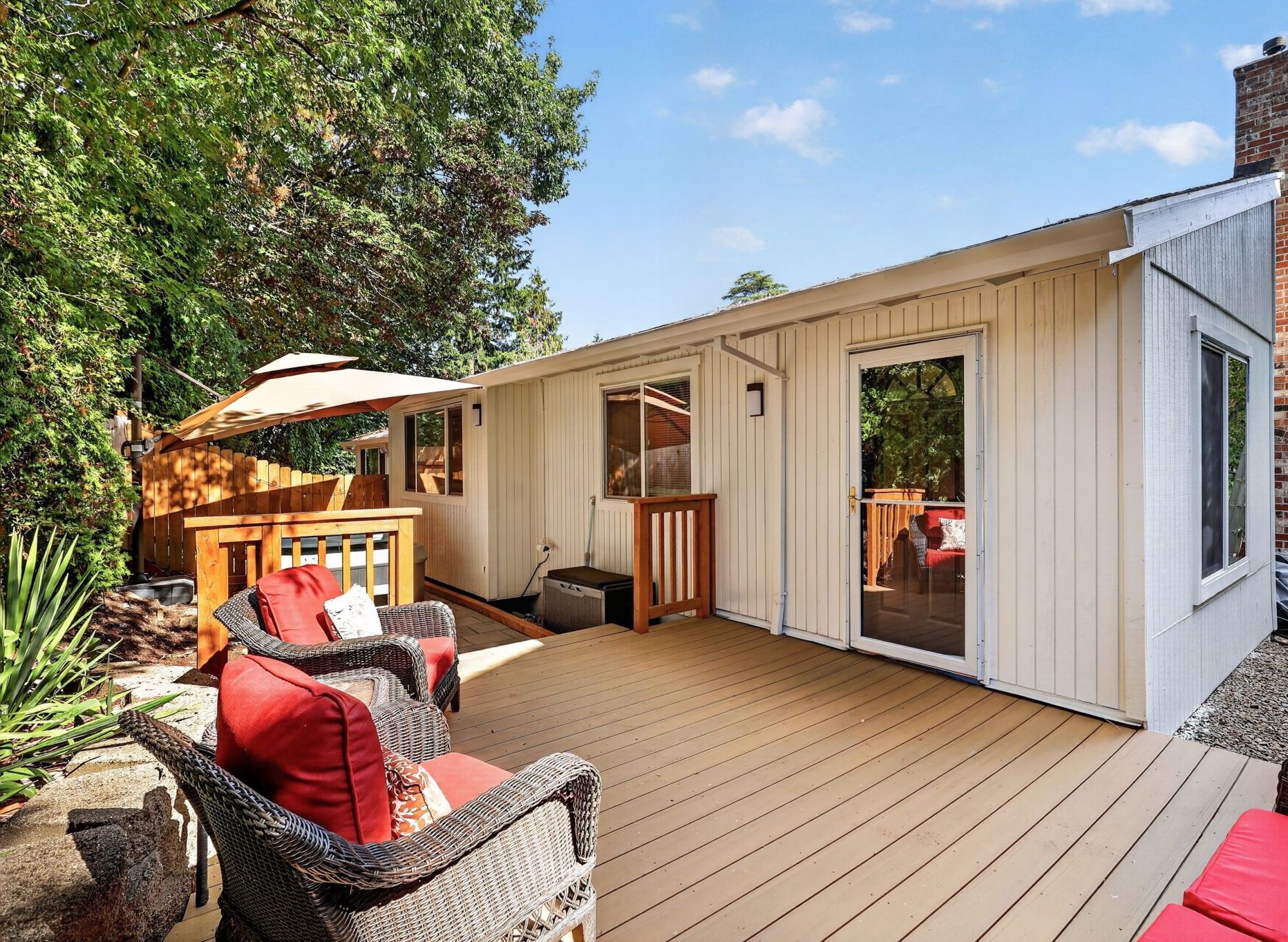 A wooden deck with outdoor furniture, a hot tub, and a covered area with a table and chairs.