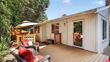 A wooden deck with outdoor furniture, a hot tub, and a covered area with a table and chairs.