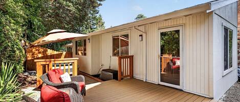 A wooden deck with outdoor furniture, a hot tub, and a covered area with a table and chairs.