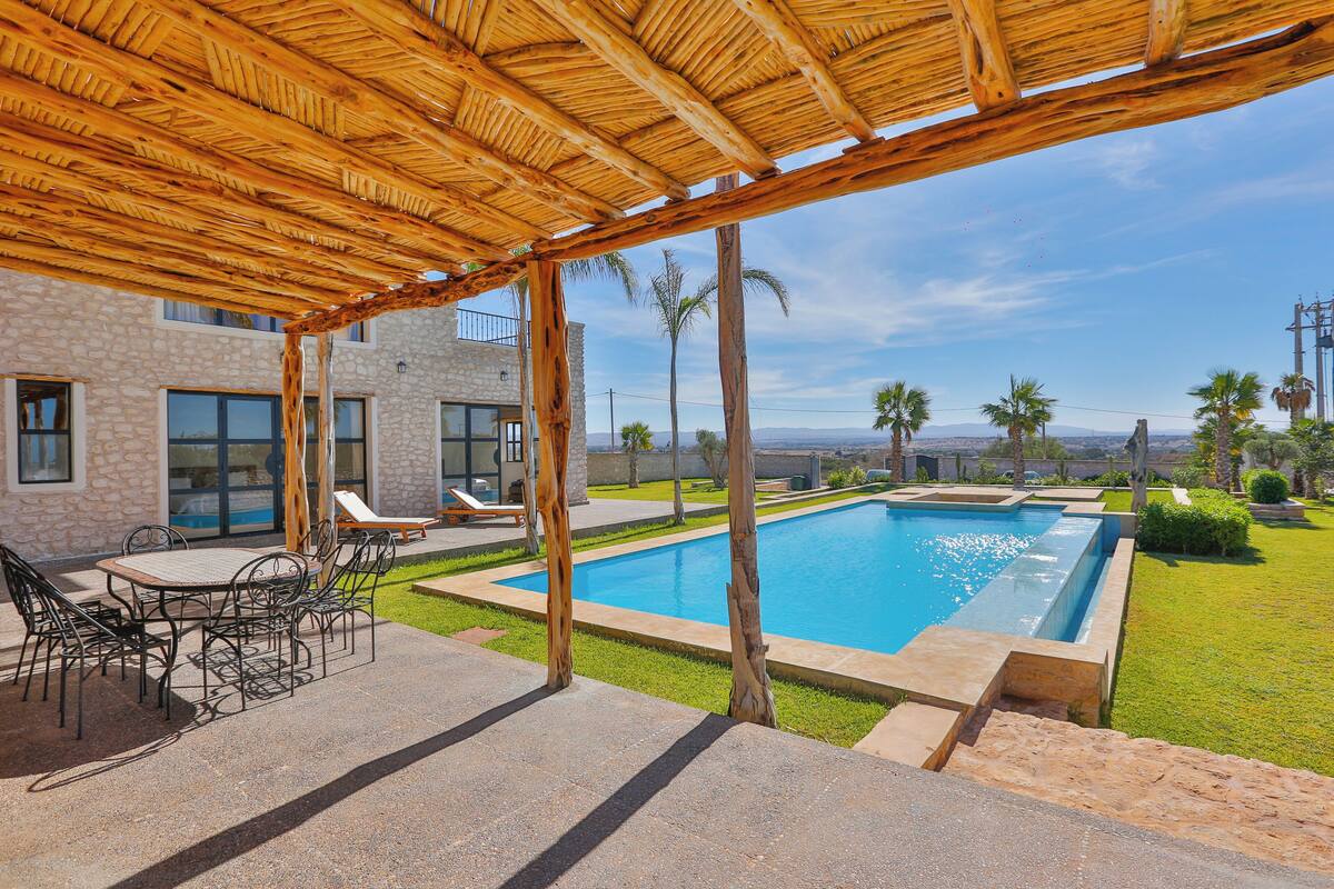 A poolside area with a pergola, outdoor seating, and a view of the pool.