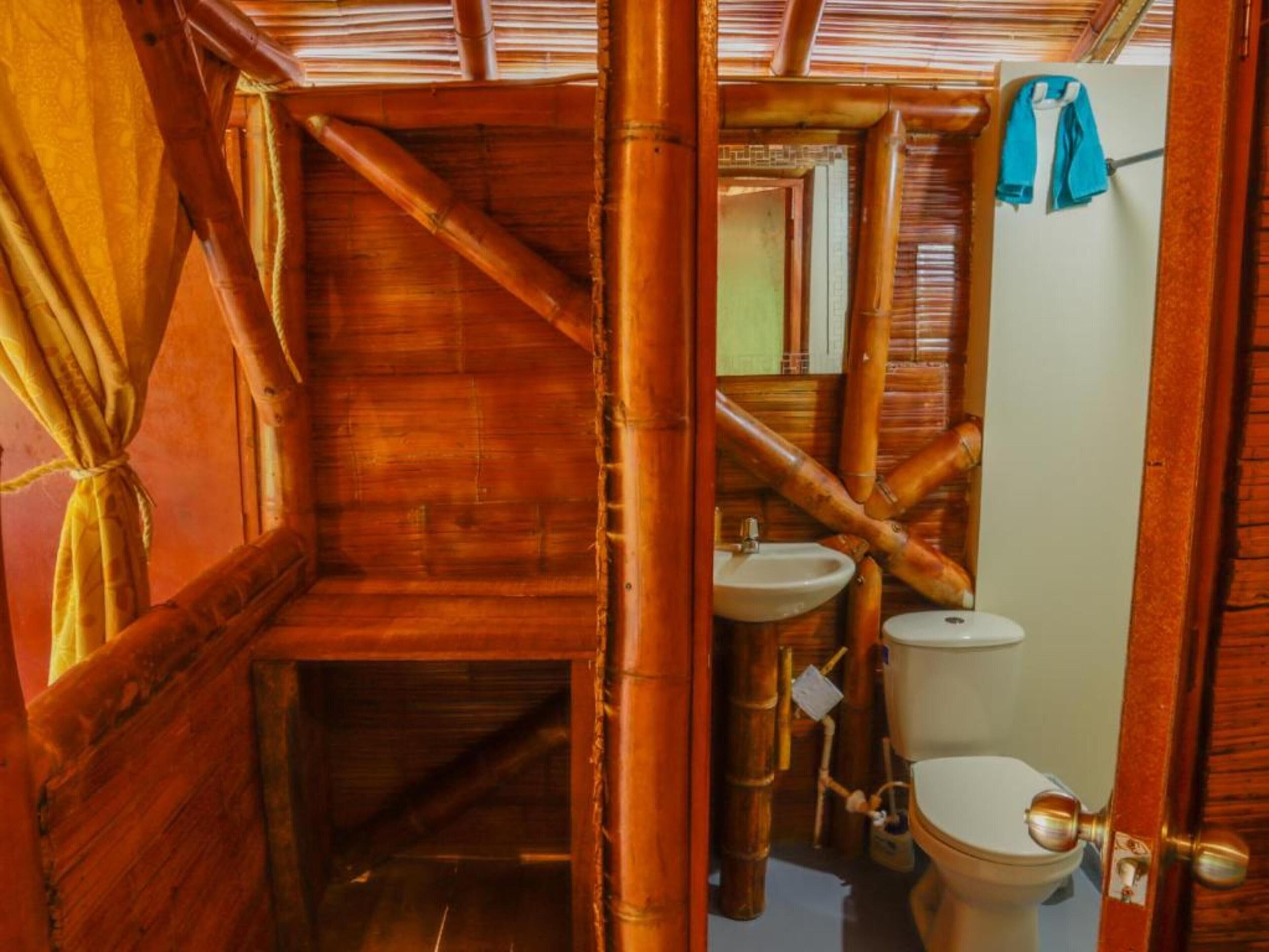 Een houten interieur met een toilet, wastafel en spiegel.