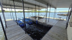 A covered dock area with a pool table, seating, and a view of the water. - Ozarks Lake House, Private Dock w/ Boat and Jetski lifts! (Rocky Mount)