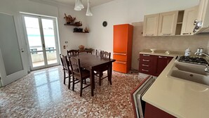 Une cuisine équipée d’une table à manger, de chaises, d’un réfrigérateur, de placards et d’un évier.
