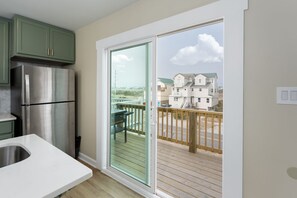 Enjoy meals in the kitchen with a refrigerator and white countertop, and step out to the adjacent balcony with a deck overlooking a residential area.