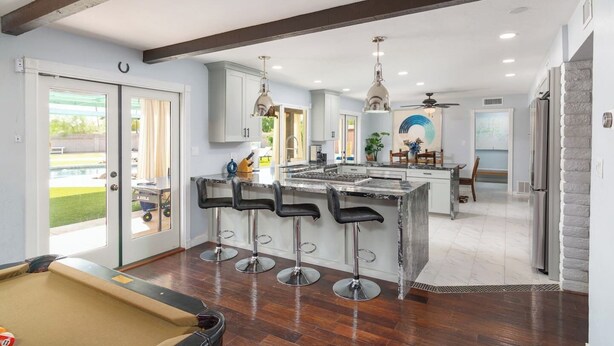 A modern kitchen with a central island, bar stools, pendant lighting, and a view of a pool. - HUGE YARD + Pool|Billiards|PingPong|Putting Green (Scottsdale)