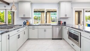 A modern kitchen with white cabinets, a stainless steel dishwasher, and a built-in oven. - HUGE YARD + Pool|Billiards|PingPong|Putting Green (Scottsdale)