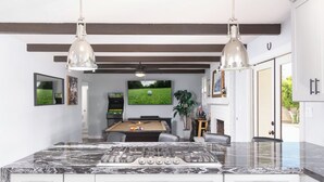 A spacious kitchen with a marble countertop, a pool table, and a ceiling fan. - HUGE YARD + Pool|Billiards|PingPong|Putting Green (Scottsdale)