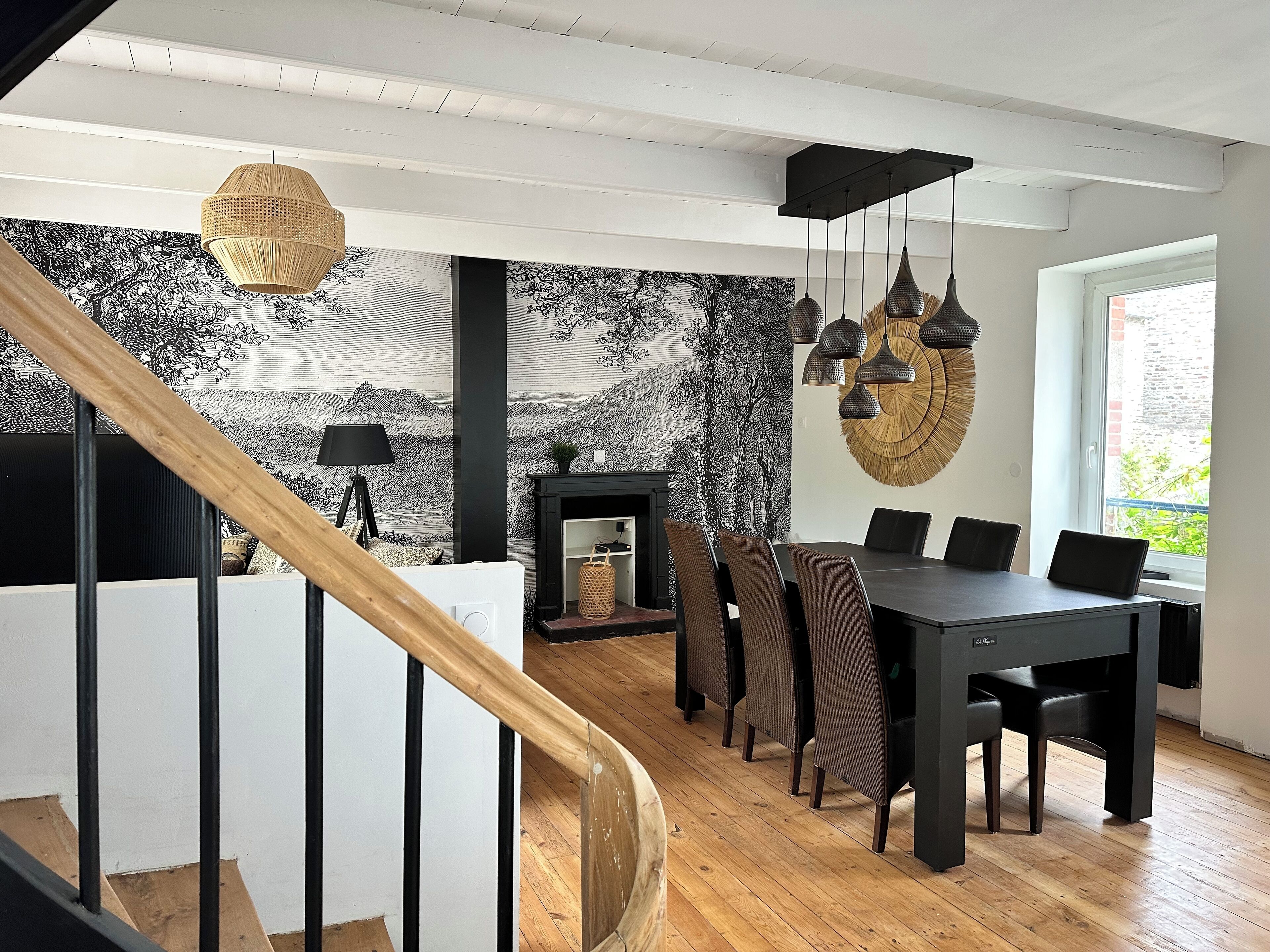 Un'area pranzo moderna con un tavolo e sedie neri, un caminetto e una scala che conduce a un altro piano.