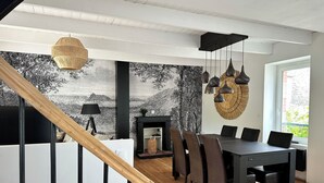 A modern dining area with a black table and chairs, a fireplace, and a staircase leading to another level. - Maison Entièrement Rénovée Avec Billard en Plein Cœur du Légué et à 5 min Plage (Plérin)