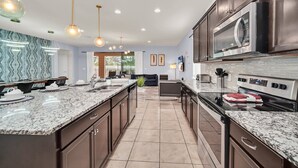 A modern kitchen with granite countertops, stainless steel appliances, and pendant lighting.