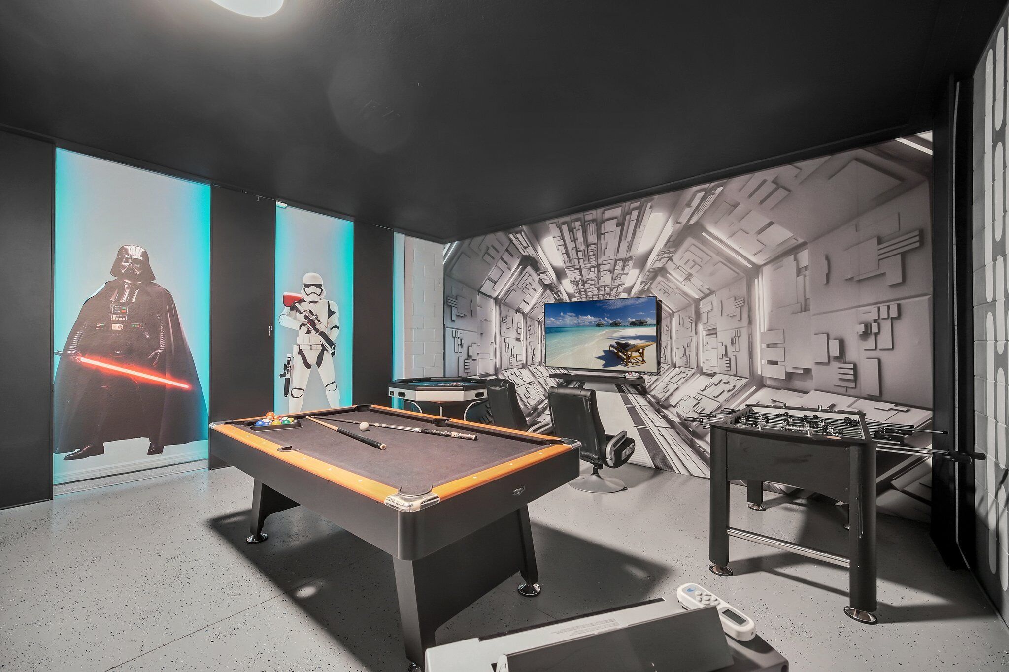 A room with a pool table, foosball table, and Star Wars-themed decorations.