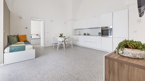 A compact, modern apartment with a kitchenette, a dining area, and a bedroom with a bed and seating area. - La Piccola Corte - Appartamento1 by BarbarHouse (Maruggio)