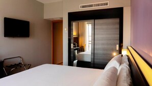 A hotel room with a bed, a TV mounted on the wall, a chair, and a mirror reflecting the room. - Tryp Cordoba Ex Tryp Los Gallos (Córdoba)