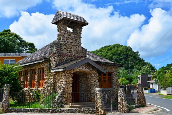 A stone building with a chimney, wooden shutters, and a metal fence. - Oceanfront Oasis SOLAR POWERED beachfront w/ spectacular ocean view (Arecibo)