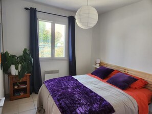 A bedroom with a bed, a bedside table, a lamp, a window with curtains, and a potted plant. - Nice family home in La Ciotat (La Ciotat)