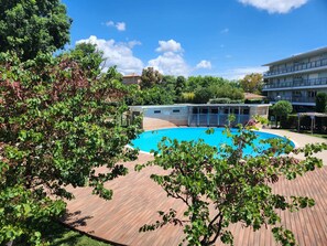 A swimming pool surrounded by a wooden deck, with buildings in the background. - Nice family home in La Ciotat (La Ciotat)