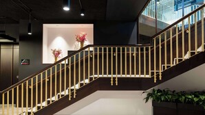 A modern staircase with a wooden handrail and glass railings, leading to an upper level. - Radisson RED Galway (Galway)