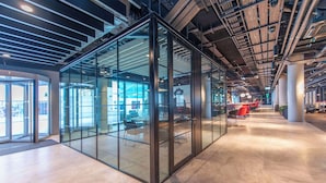A modern office space with glass partitions, a central seating area, and a visible staircase. - Radisson RED Galway (Galway)