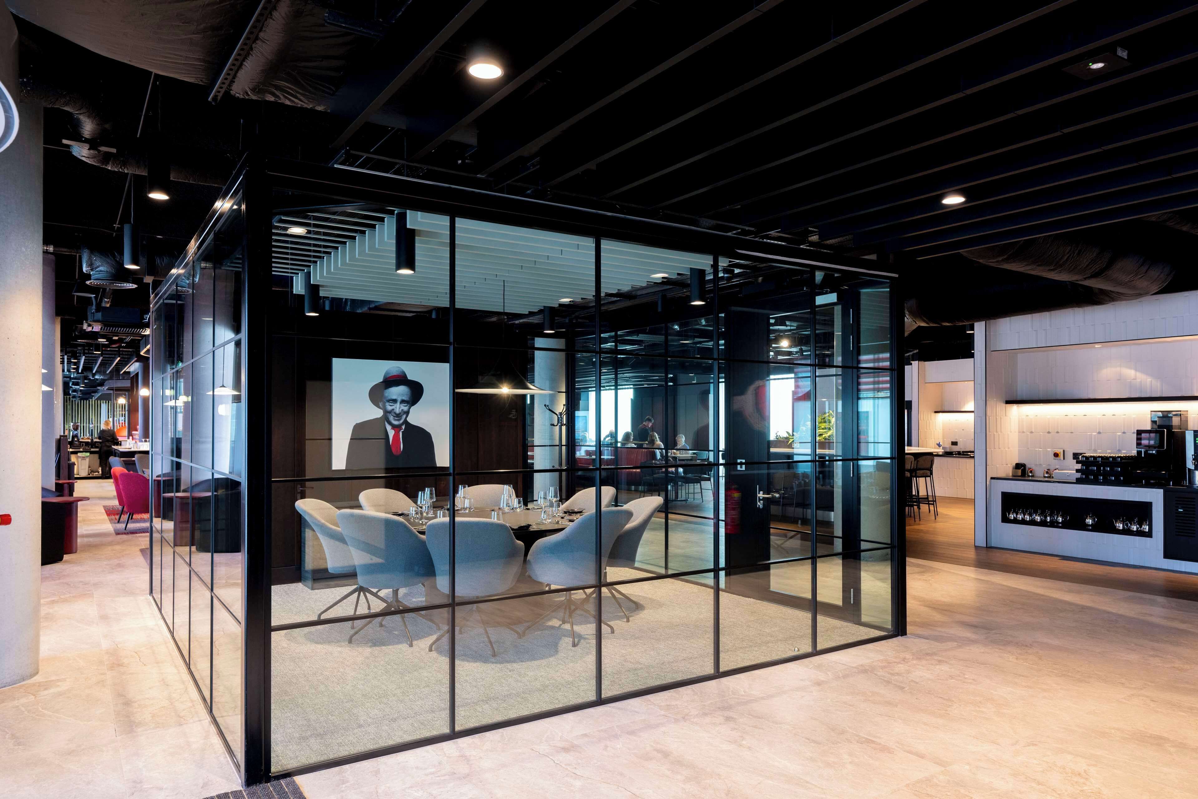 A modern conference room with glass walls, a round table, and contemporary chairs.