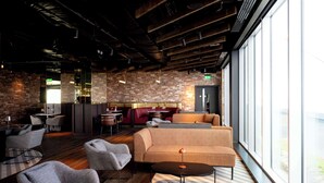A modern interior with a brick wall, a sofa, chairs, a table, and a bar area. - Radisson RED Galway (Galway)