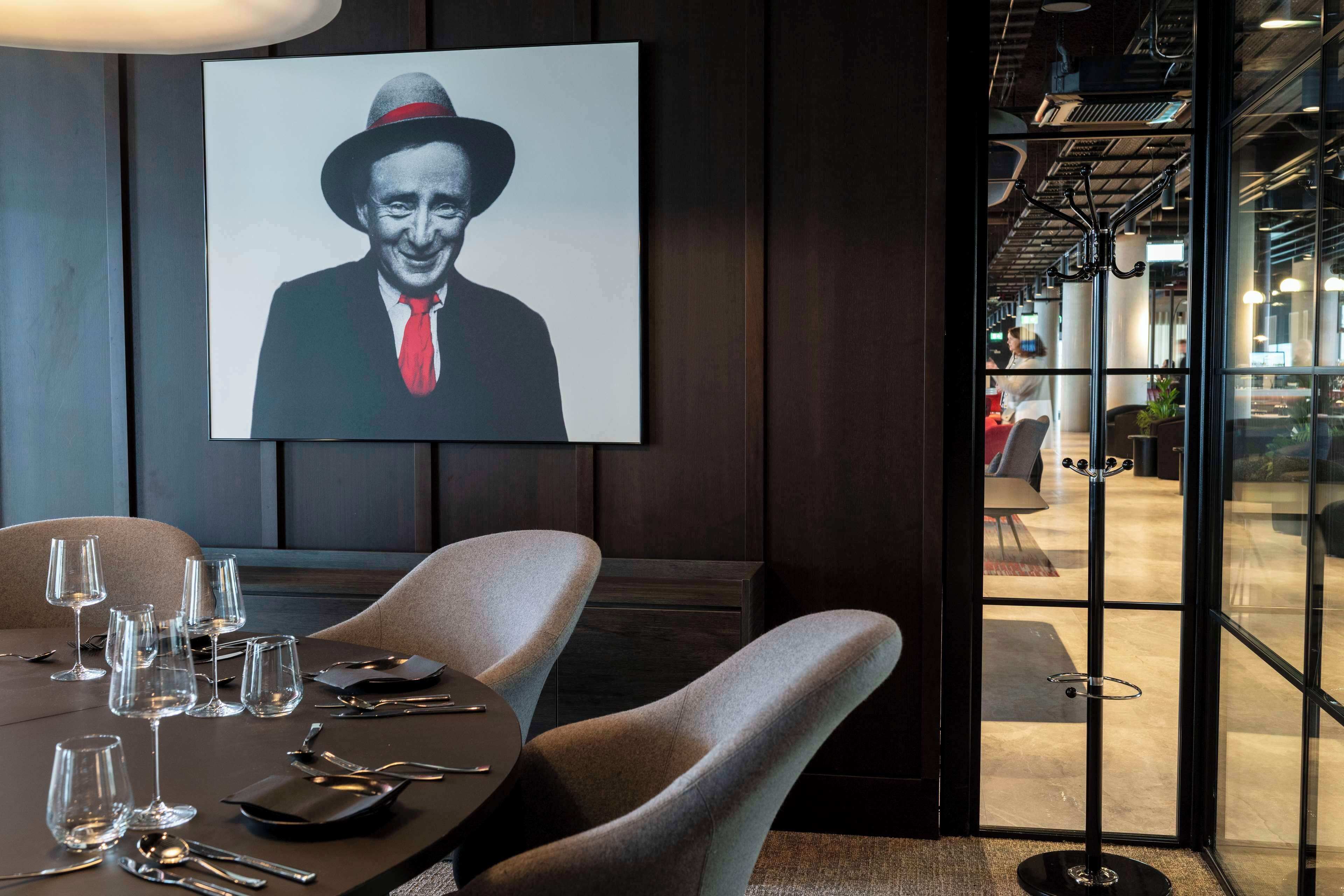 A dining area with a table set for six, a framed portrait on the wall, and a view into the adjacent space.