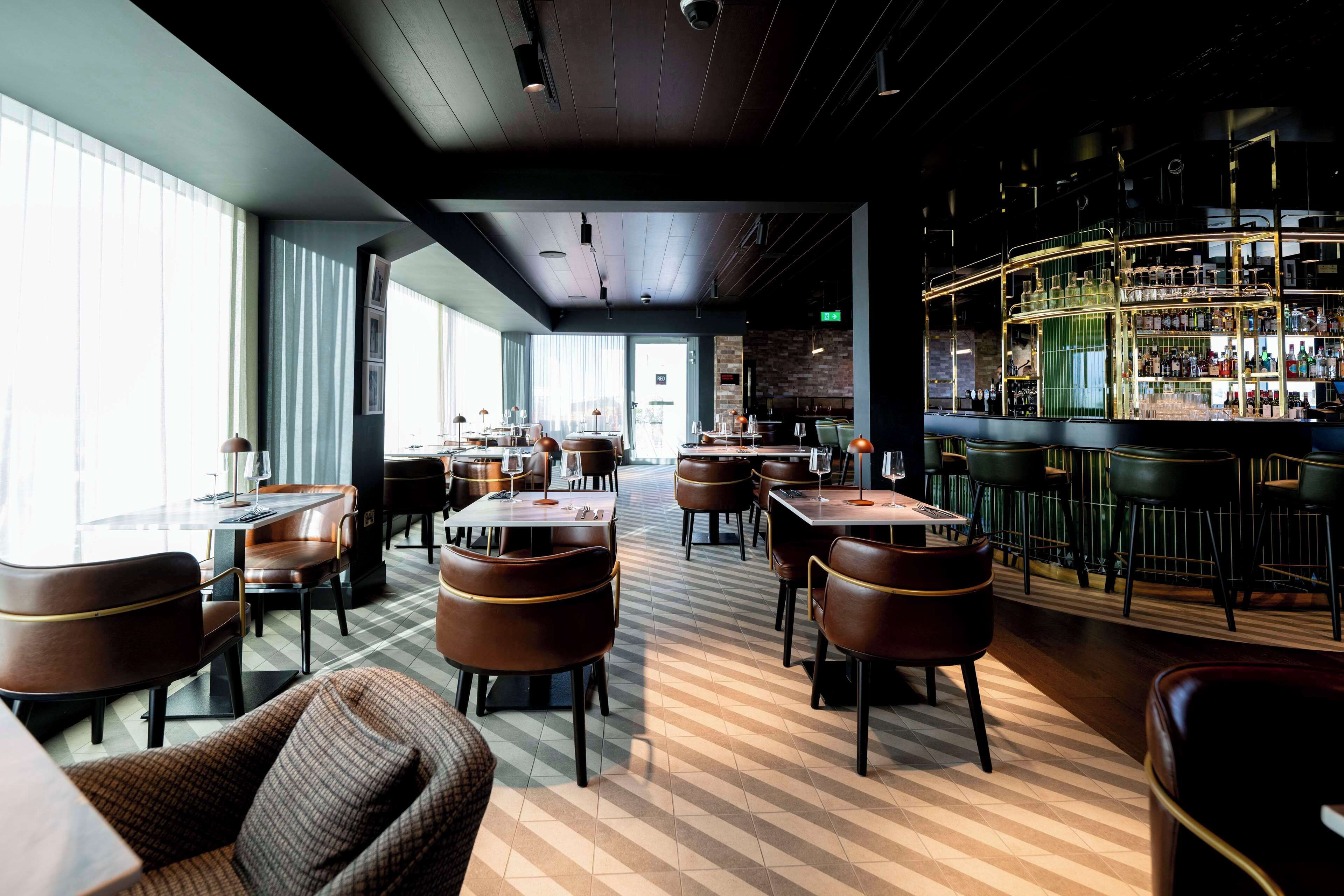 Eine moderne Bar mit Schachbrettboden, Ledersitzmöglichkeiten und einer gut beleuchteten Bar.