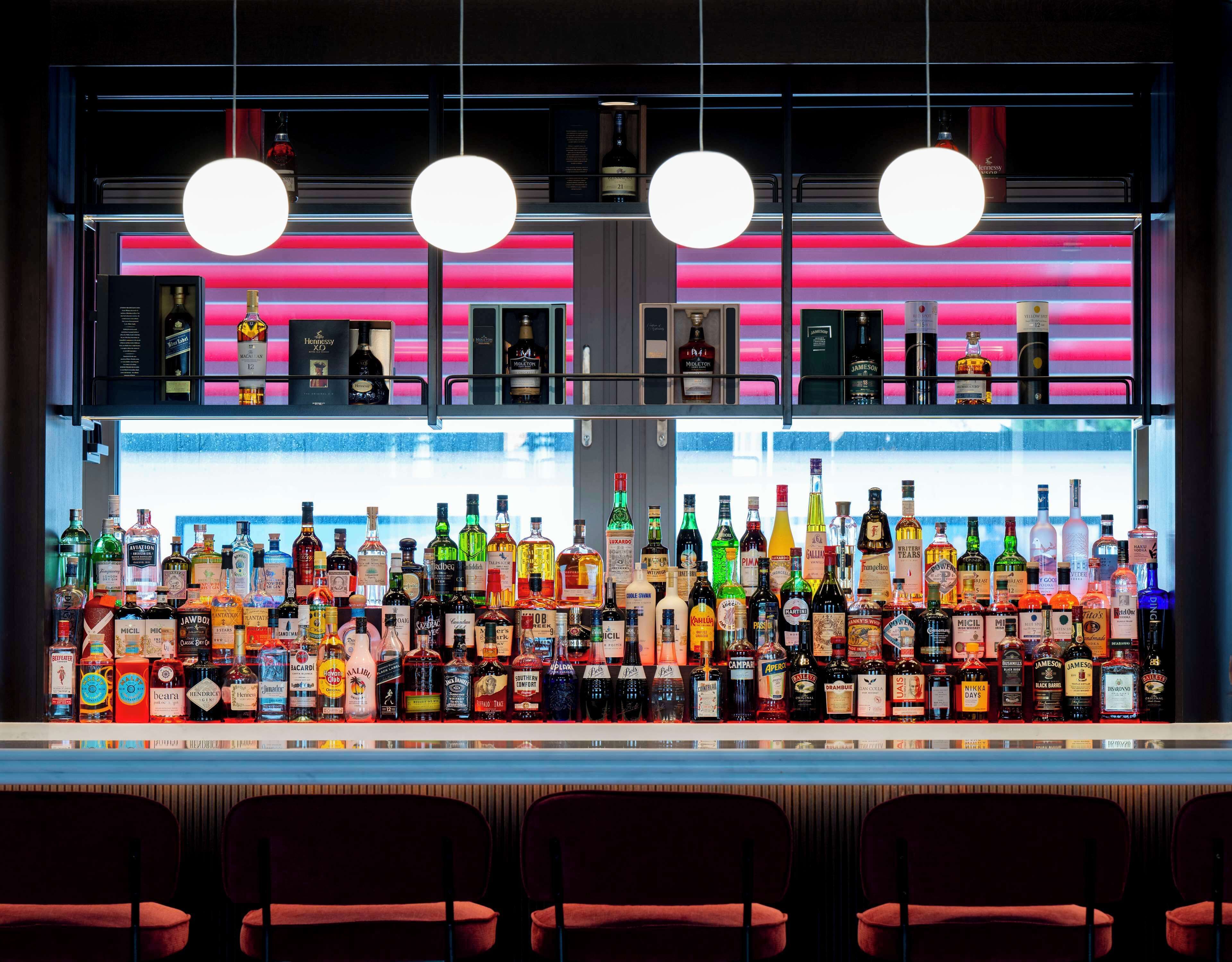 A bar with a variety of liquor bottles and a neon-lit background.