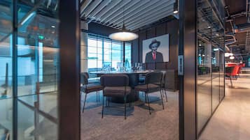 A modern office space with a round table, chairs, and a large window.