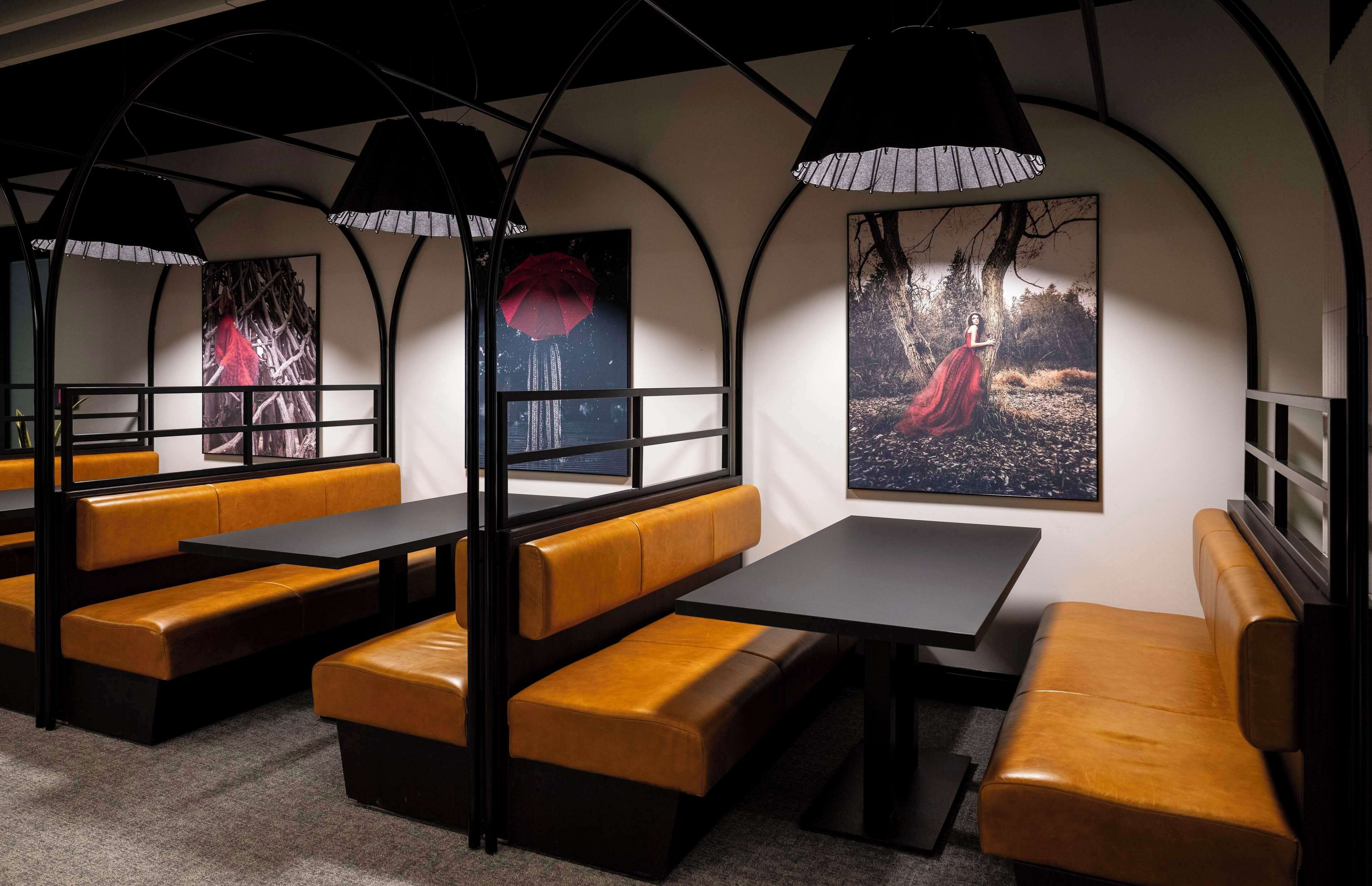 A restaurant with booth seating, black tables, and pendant lighting.