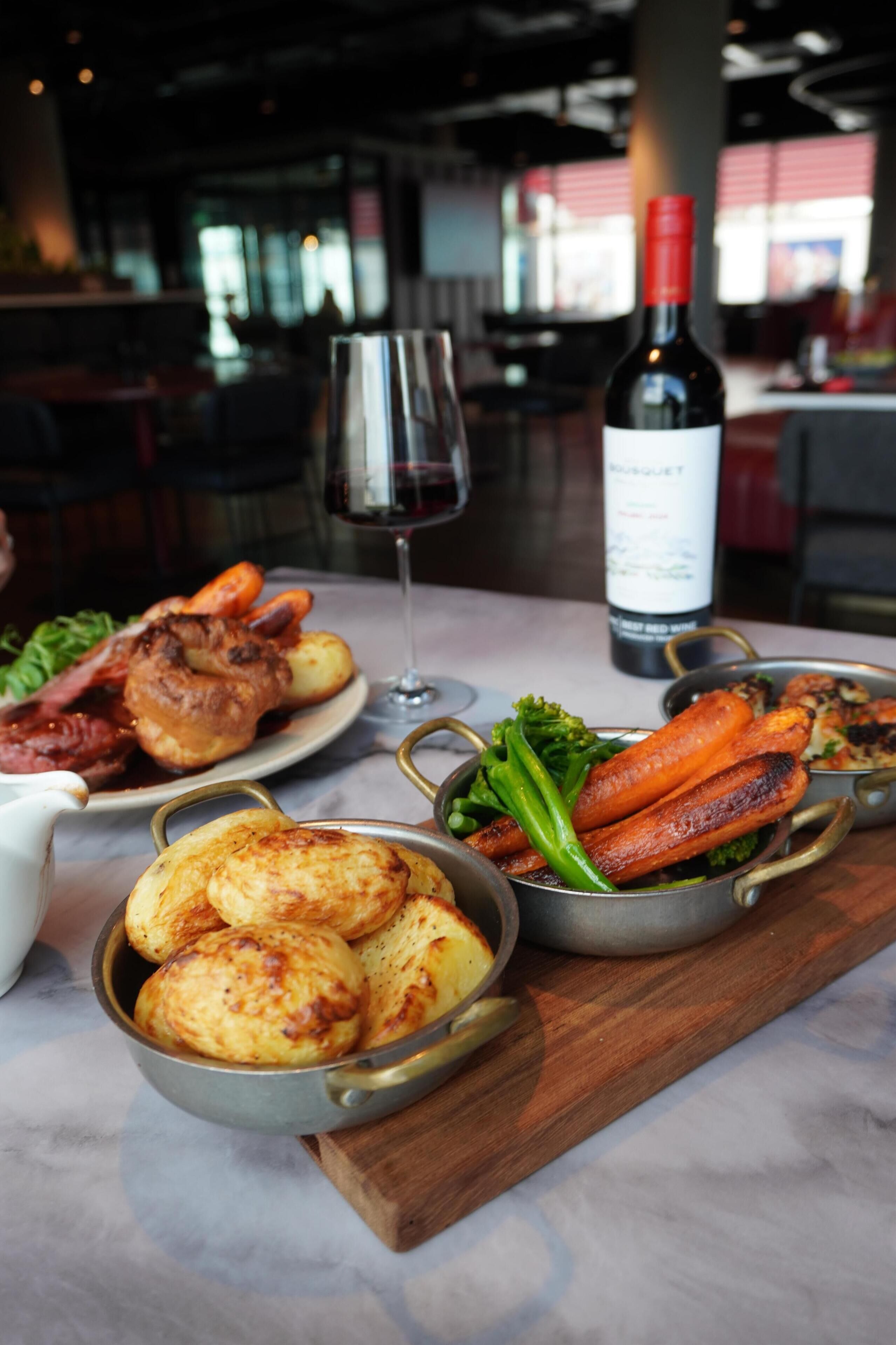 A dining table with various dishes, a wine bottle, and a glass of red wine.
